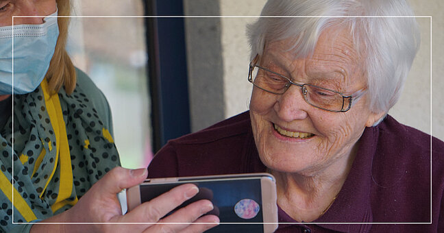 Alte Frau schaut auf Smartphone