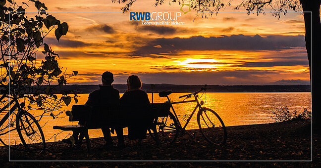 Pärchen sitzt auf Bank am See bei Sonnenuntergang