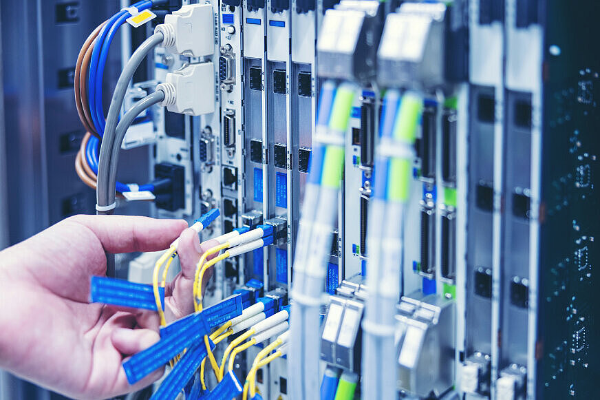 Eine Hand steckt ein Kabel in Netzwerktechnik